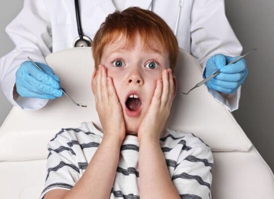 Scared young child sitting in a dental chair, gripping the armrests with a worried expression