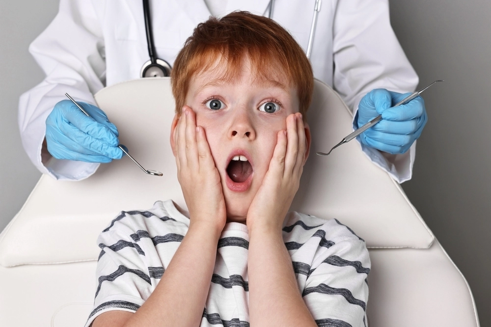 Scared young child sitting in a dental chair, gripping the armrests with a worried expression