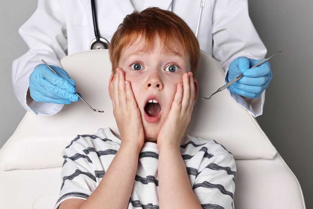 Scared young child sitting in a dental chair, gripping the armrests with a worried expression